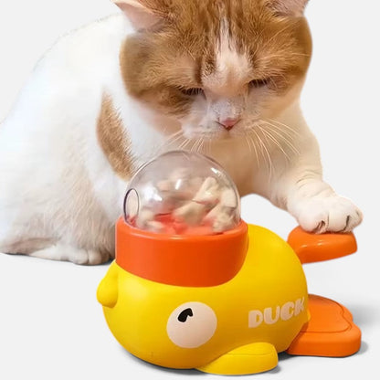 Tailora cat playing with a yellow and orange duck-shaped interactive treat dispenser toy on a white background