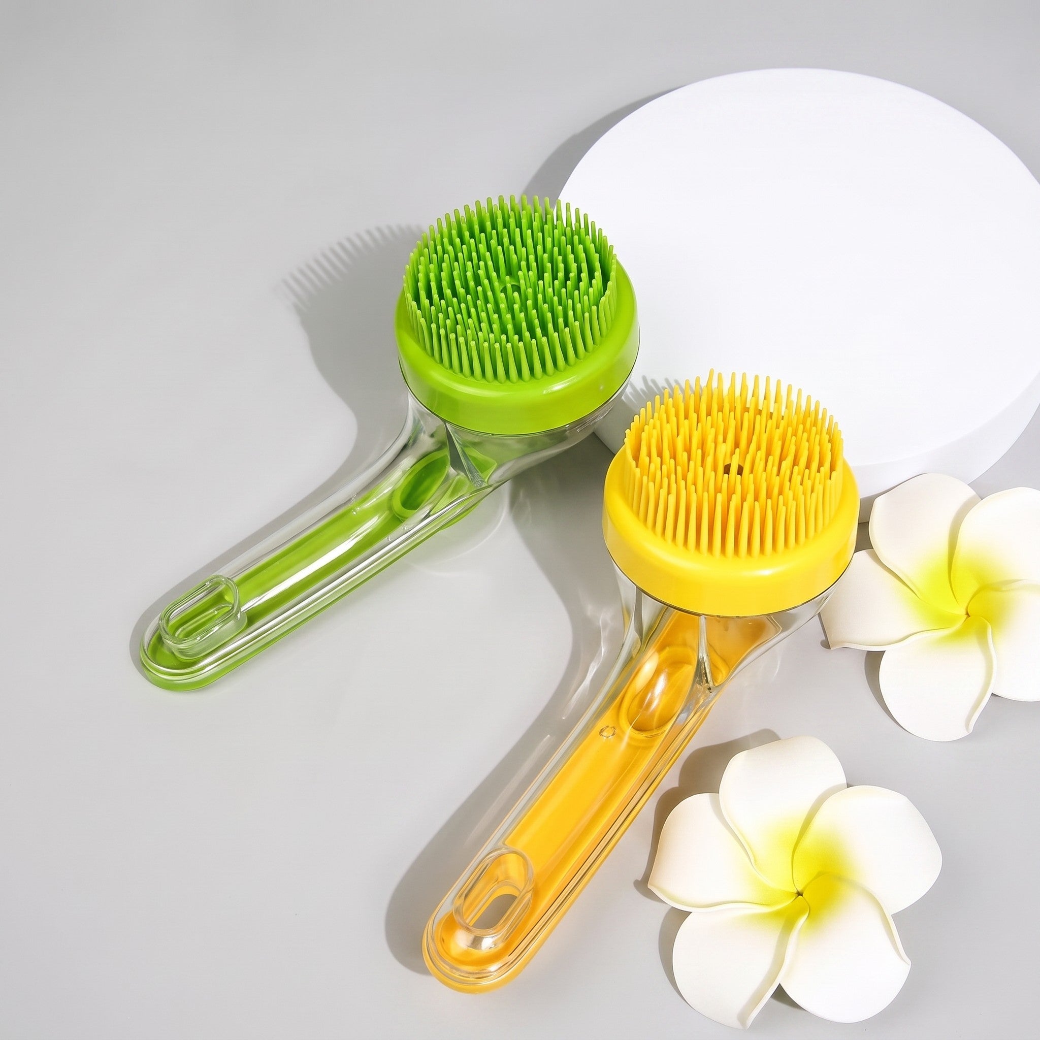 Tailora 2-in-1 pet bath brushes in green and yellow with soft silicone bristles and ergonomic handles on a grey surface