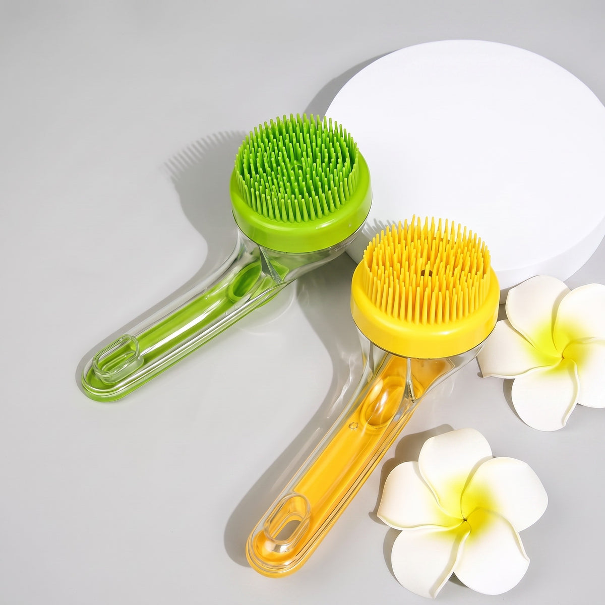 Tailora 2-in-1 pet bath brushes in green and yellow with soft silicone bristles and ergonomic handles on a grey surface