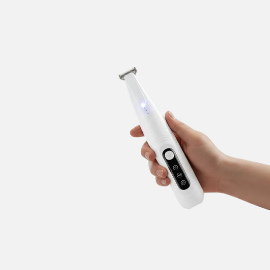 Tailora precision pet trimmer with LED light, held in hand, featuring a narrow stainless steel blade for grooming.